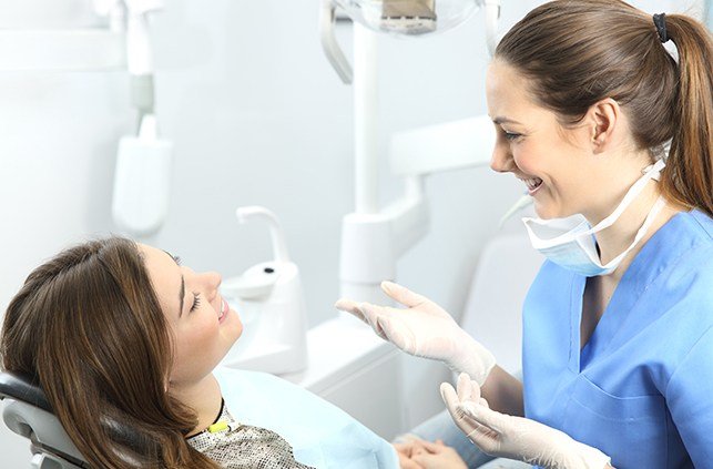 Woman in dental chair smiling at dental team member
