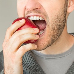 a person with dentures biting into an apple