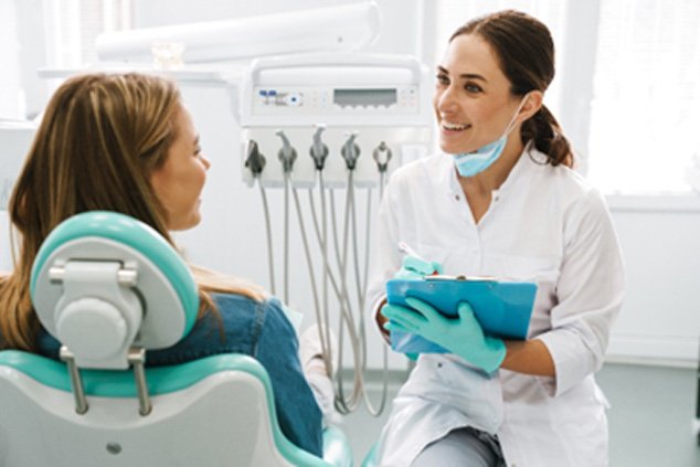 Cosmetic dentist smiling at patient while reviewing the cost