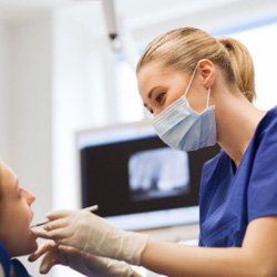 Cosmetic dentist smiling while examining patient's teeth