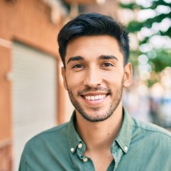 Man in green button up shirt smiling while walking outside