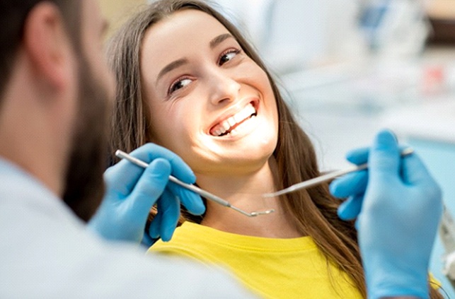 Woman smiling at her dentist after getting dental crowns in Fitchburg