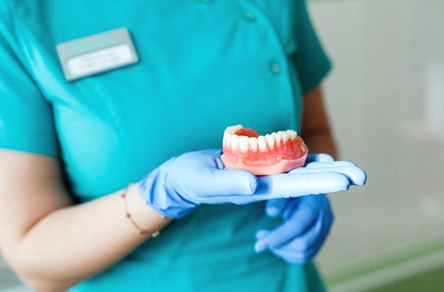 Closeup of Fitchburg dentist holding denture