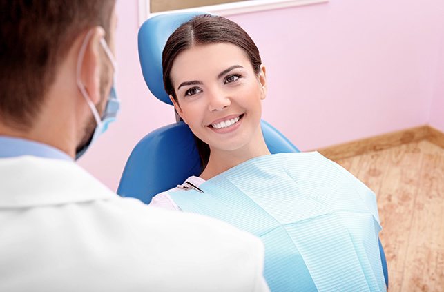 Mujer sonriendo en el sillón dental mientras mira al dentista