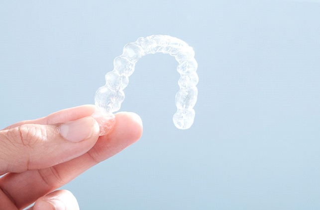 Patient holding up Invisalign in Fitchburg