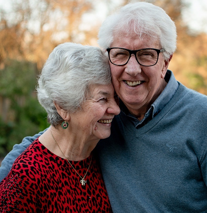 Older couple laughing together after replacing missing teeth