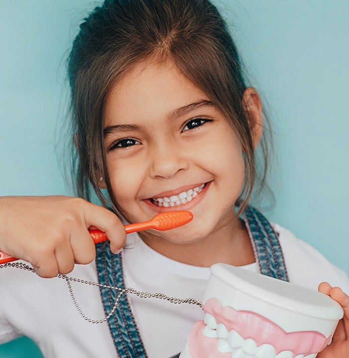 Little girl learning to brush teeth during children's dentistry visit