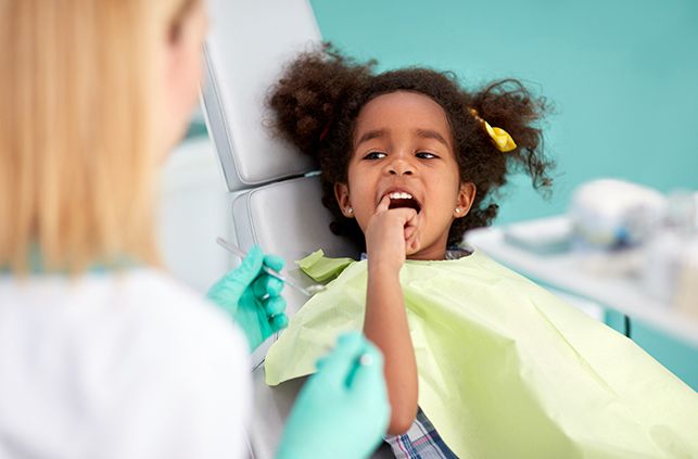Young girl pointing to smile during children's dental checkup visit