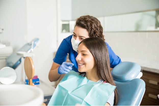 Young woman smiling in mirror with traditional braces in Fitchburg