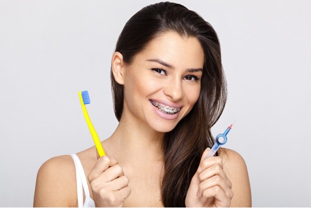 Woman with traditional braces in Fitchburg holding dental tools