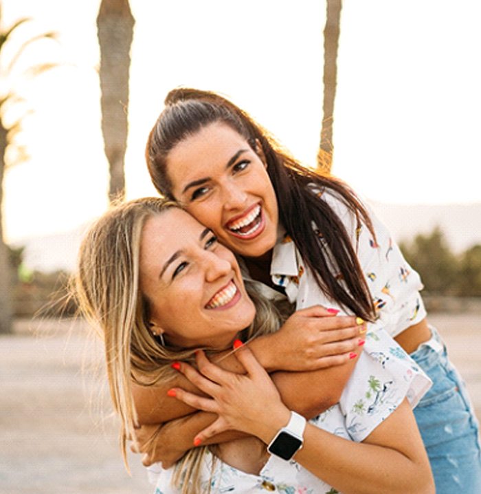 Two friends smiling while on the beach