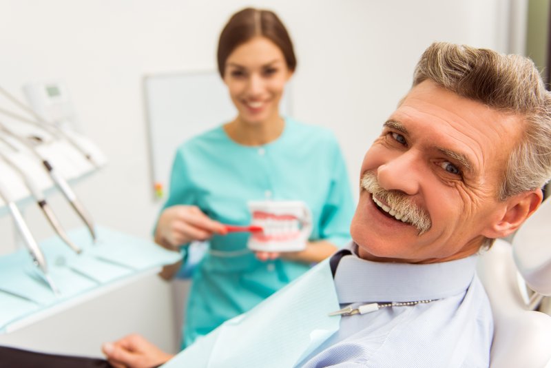 Dentist demonstrating to patient how to clean dentures