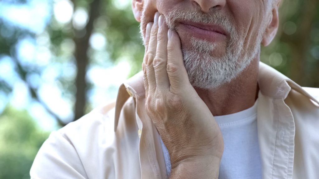 Closeup of man experiencing jaw pain on one side