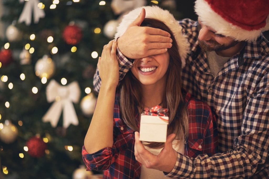 Man covering woman's eyes for surprise gift