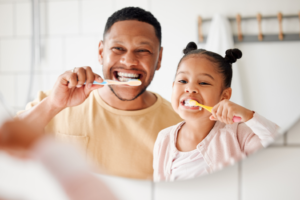 a father and his daughter brushing their teeth