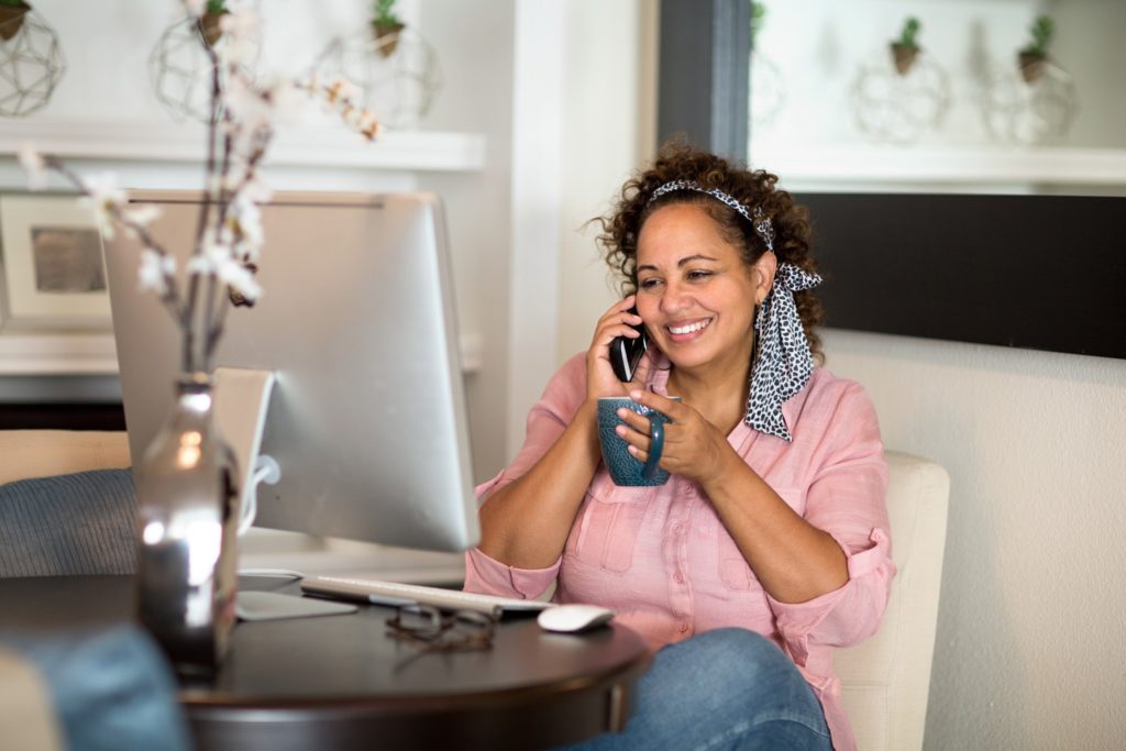 Woman smiling while talking on phone in home office