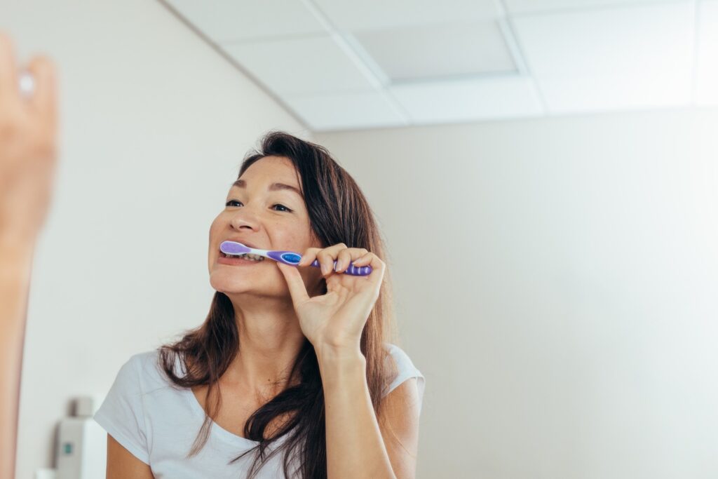 Closeup of woman brushing her teeth in bathroom